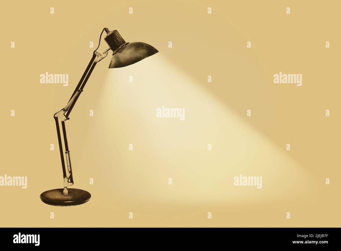 Illuminated vintage rusty desk lamp with flexible arms on a sepia background Stock Photo