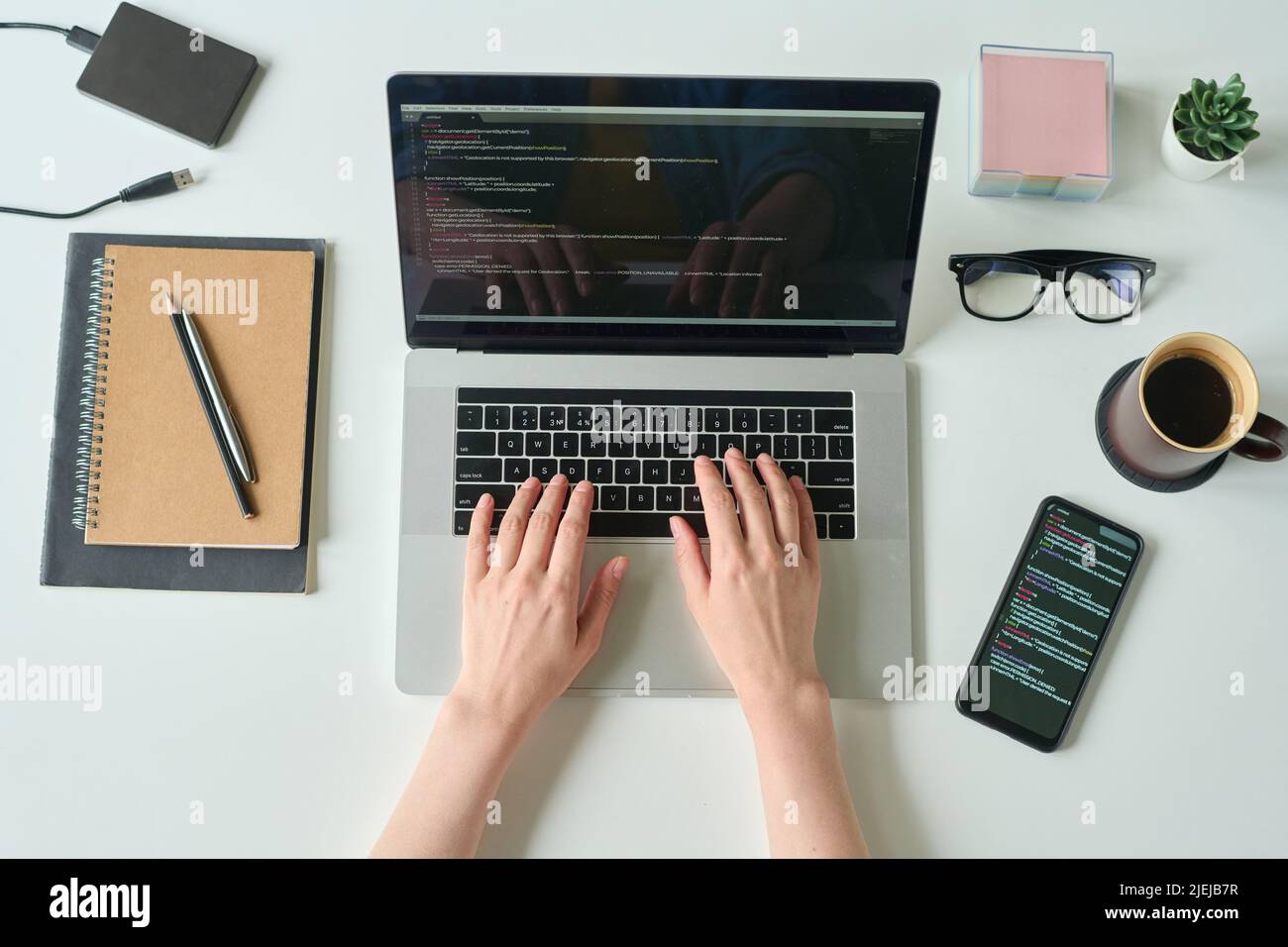 High angle view of developer programming language and program code on screen laptop working at table with smartphone and coffee drink Stock Photo