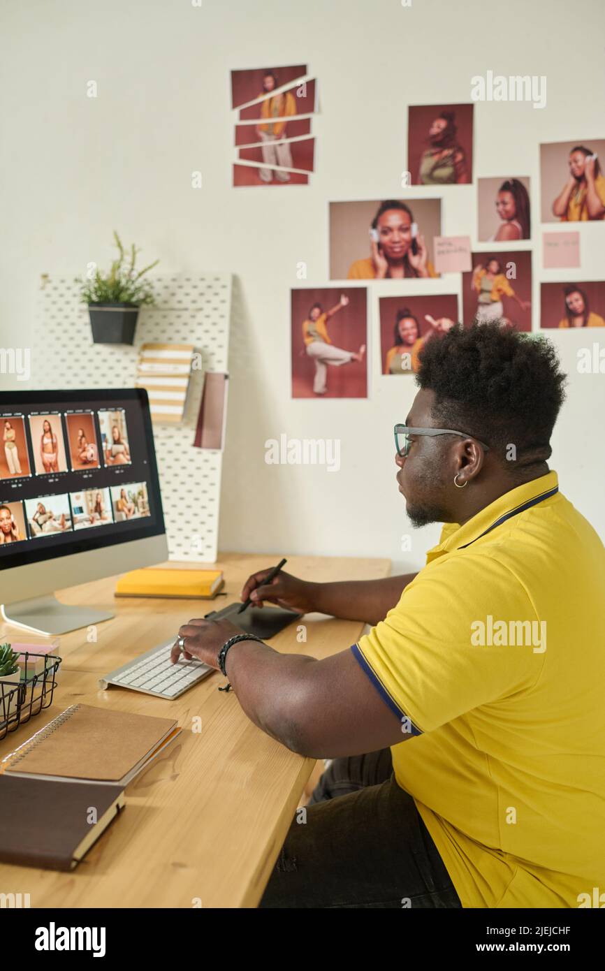 African American editor retouching professional photos on computer sitting at his workplace at office Stock Photo