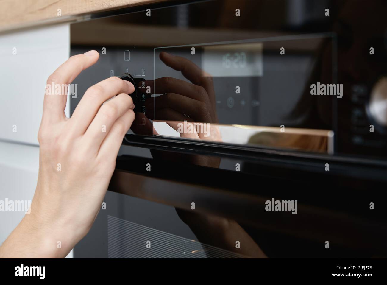 Female hand choose baking program on electric oven control panel, Woman