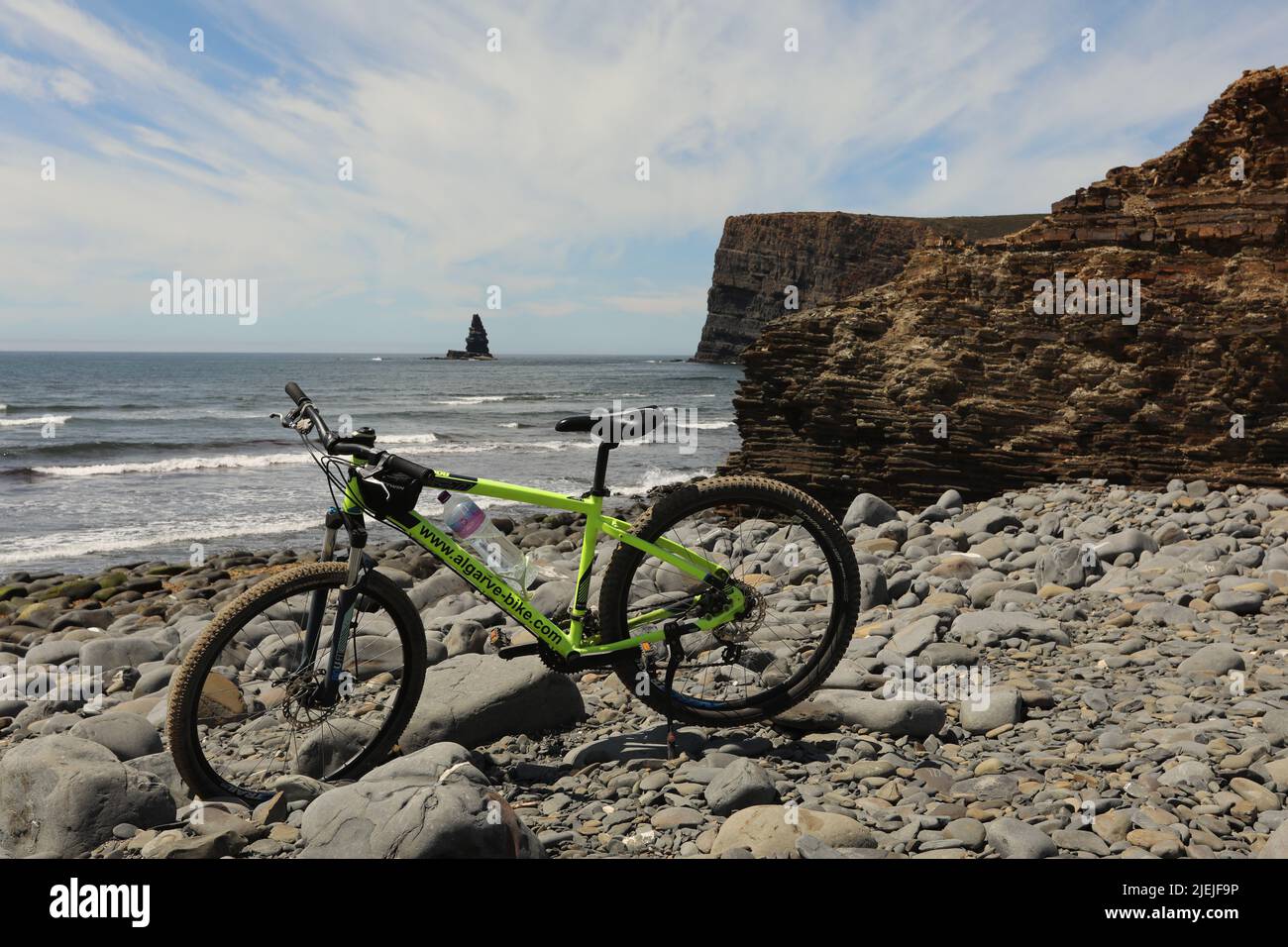 Bike on a stony beach by the sea and cliff in Portugal Stock Photo