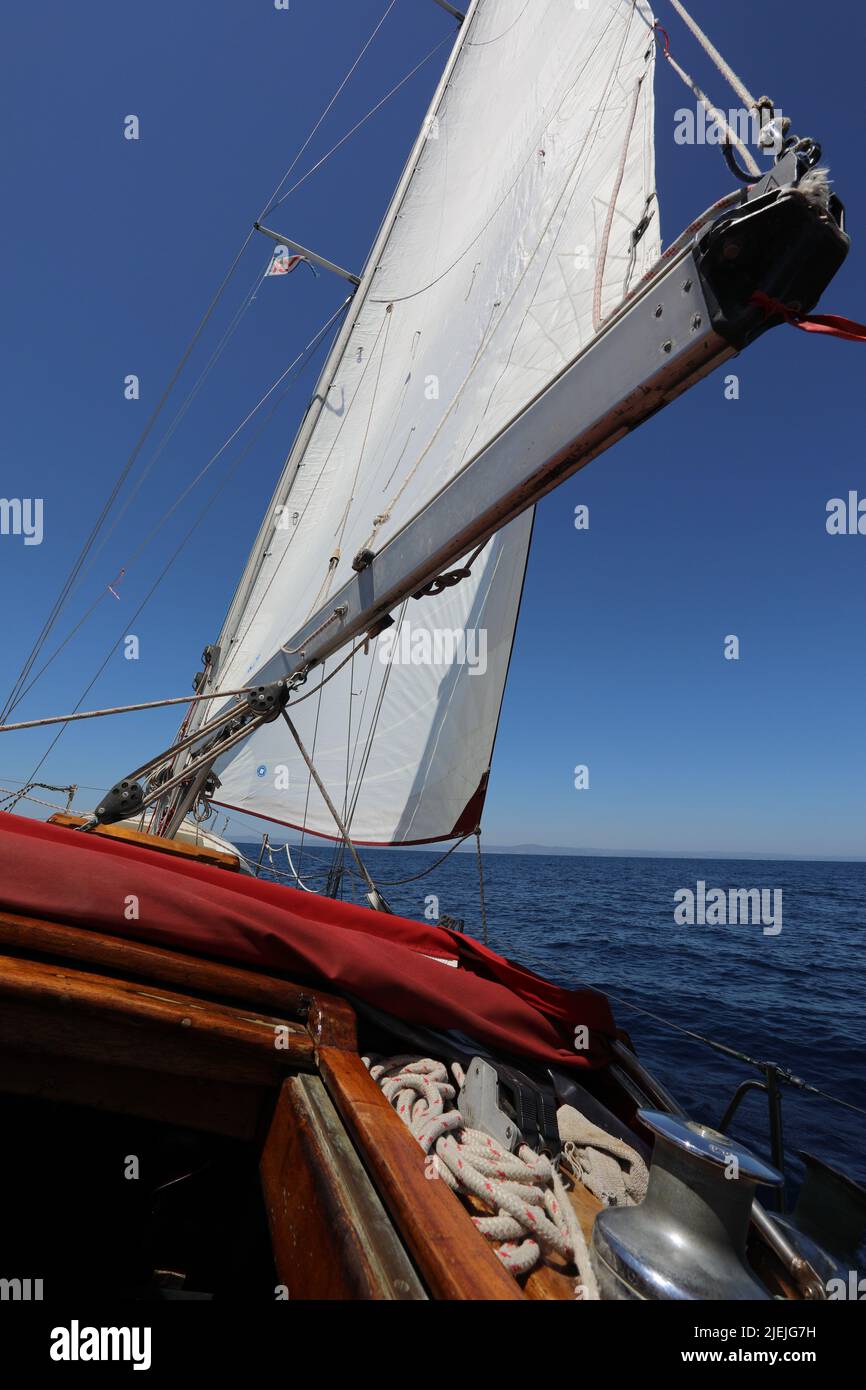 White Sail boat of vessel floating on the sea with bright sun and blue sky Stock Photo