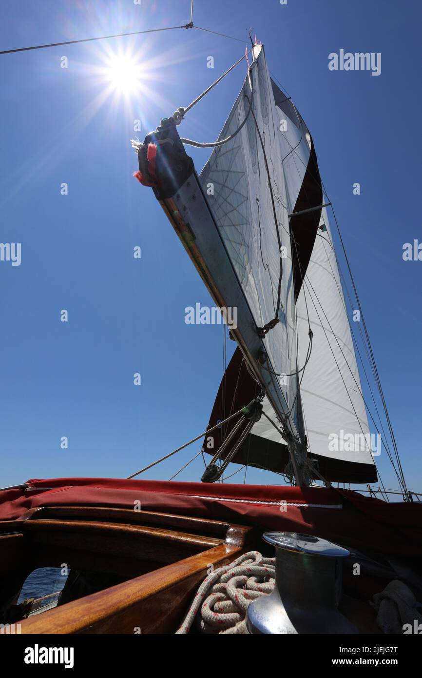 White Sailboat of the vessel floating on the sea with bright sun and blue sky Stock Photo