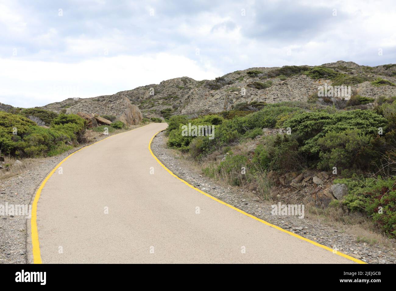 Curvy Road with yellow lines going up the mountains in Spain Stock Photo