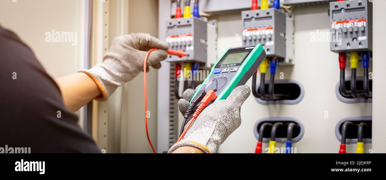Engineers working to inspect and maintain electrical control cabinets. Stock Photo
