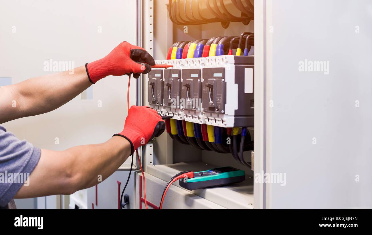 Electrical engineers check electrical control devices with a multimeter