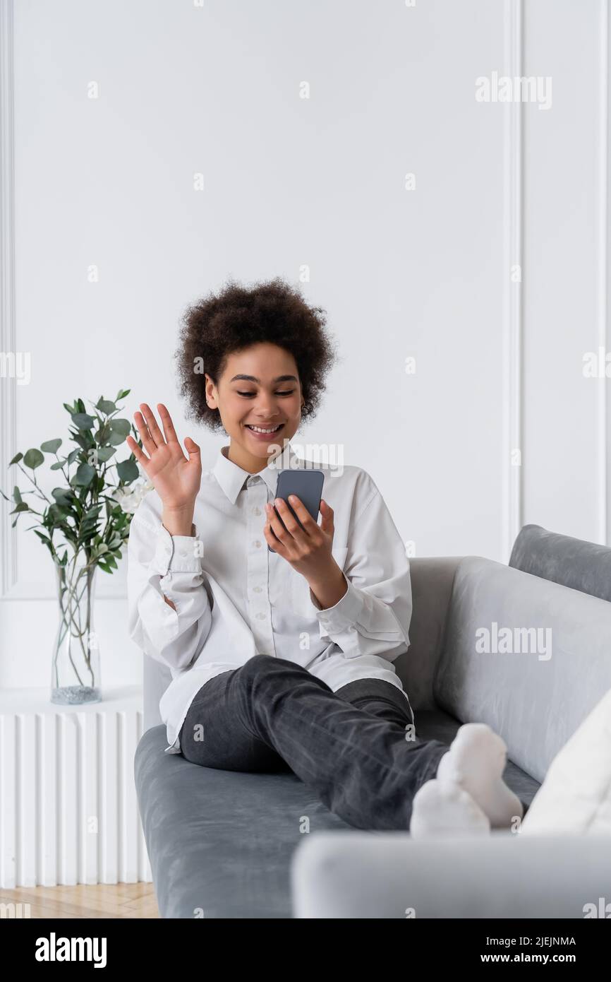 happy african american woman waving hand during video call on ...
