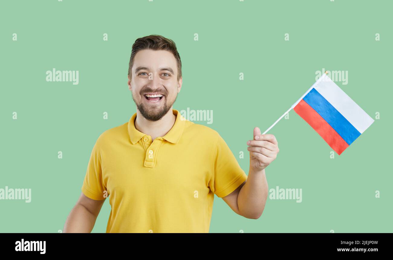 Happy Russian man isolated on green background holding flag of Russian Federation Stock Photo