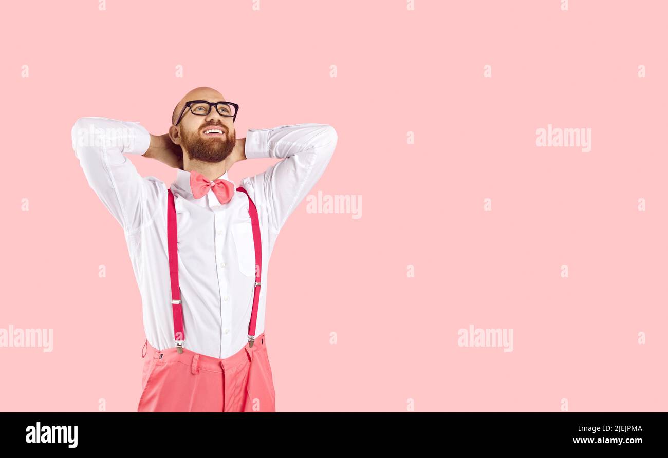 Happy man isolated on pink copy space background dreaming of something and smiling Stock Photo