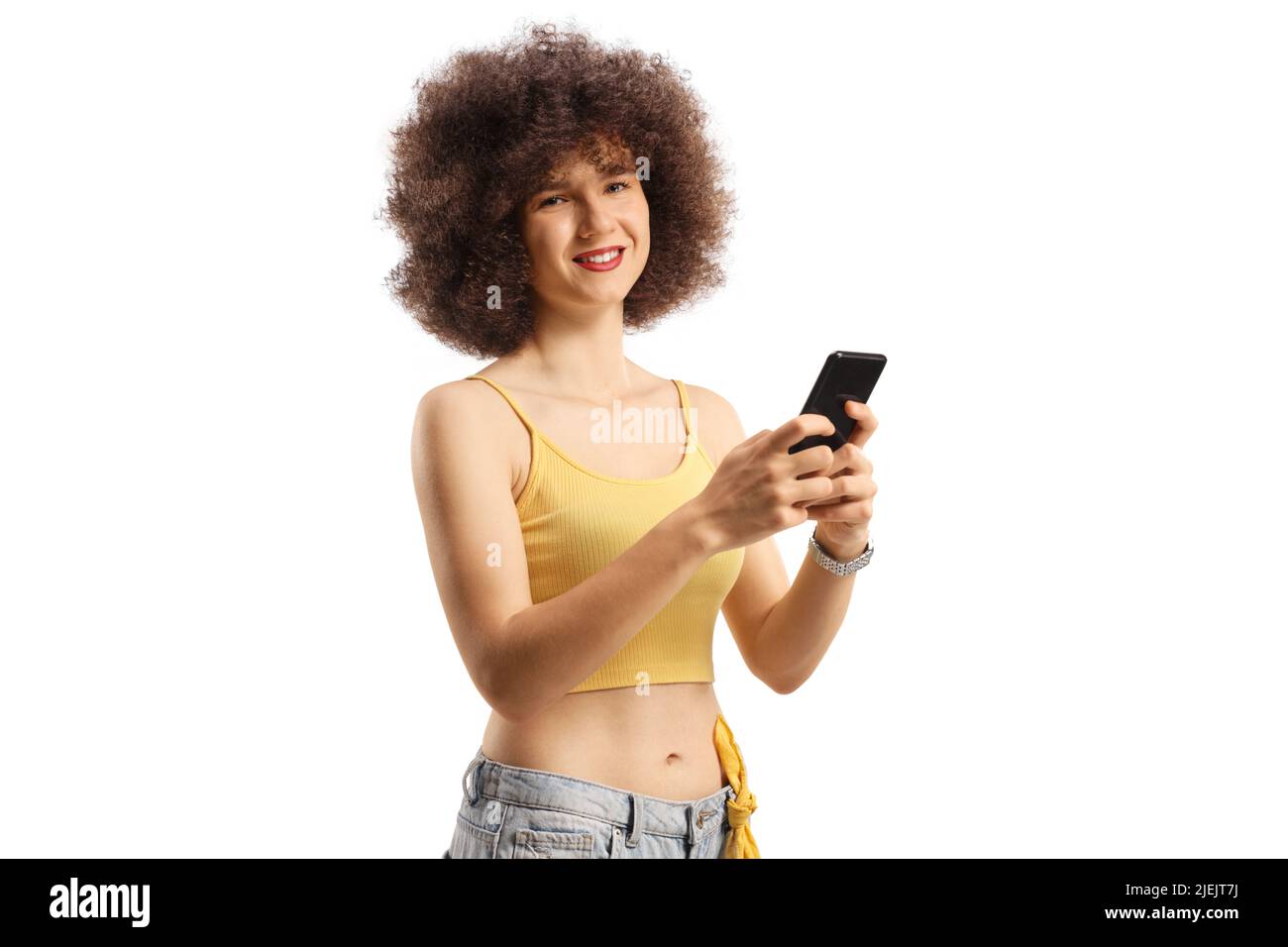 Young caucasian woman with afro hairstyle using a smartphone and looking at camera isolated on white background Stock Photo