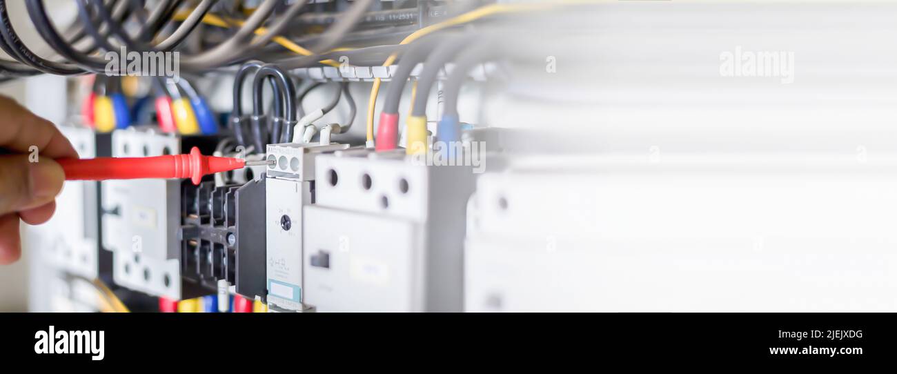 Electrical engineers check electrical control devices with a multimeter. Stock Photo