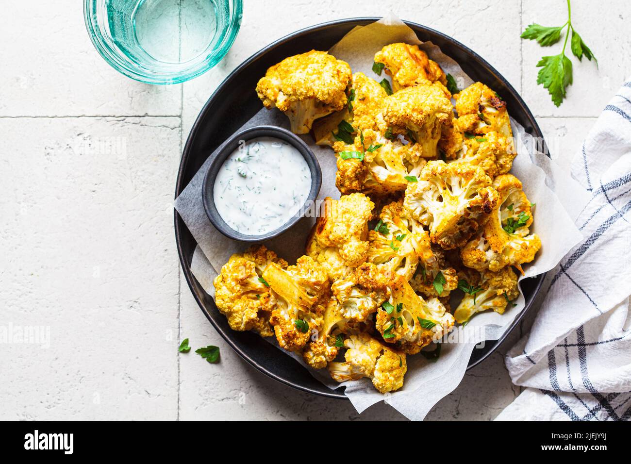 Baked spicy cauliflower wings with yogurt sauce in a black plate, top