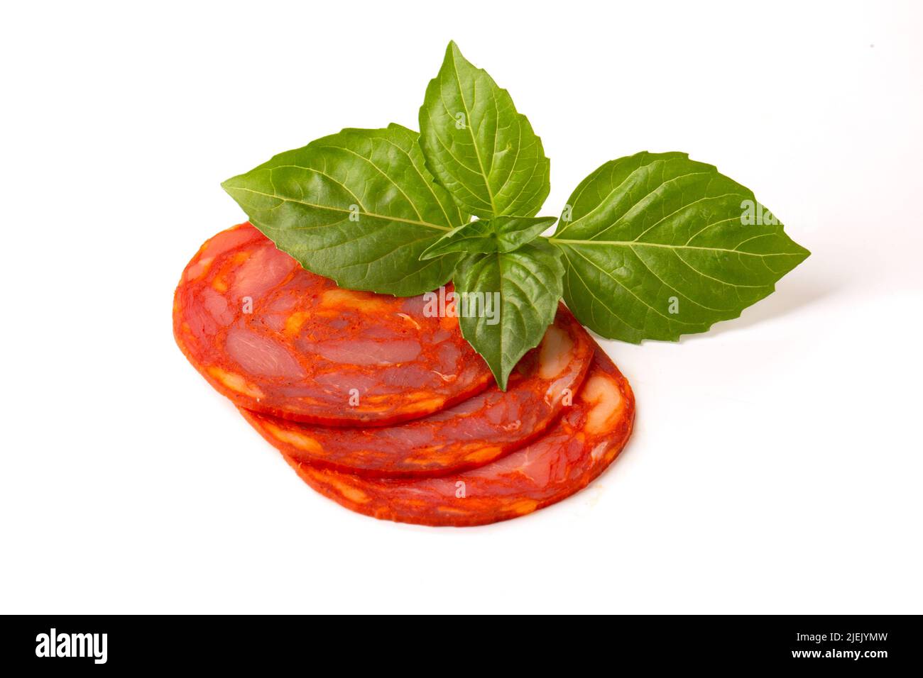 Sliced round pieces of rawcured Chorizo sausage with basil leaf on a