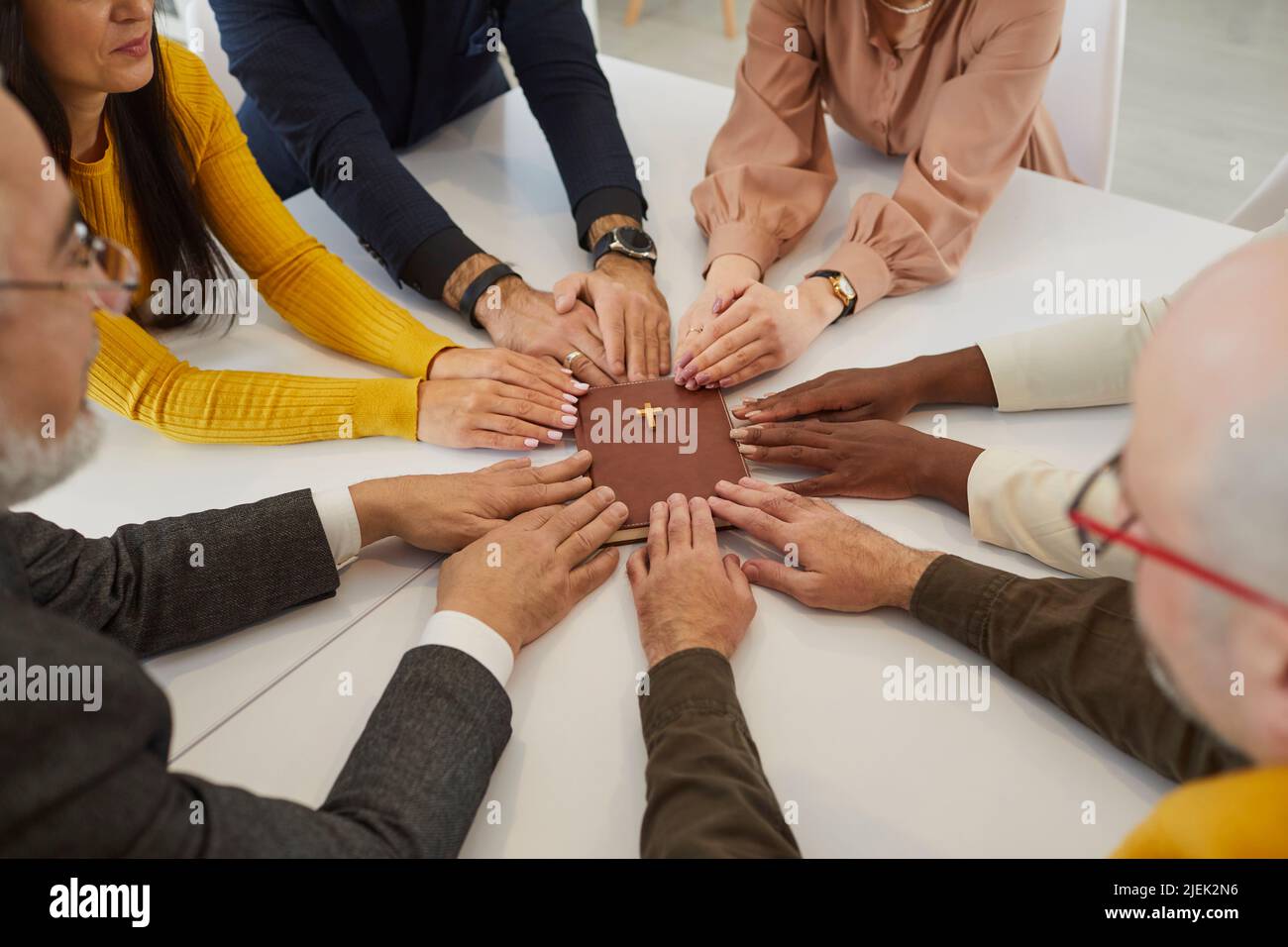 Diverse multicultural group of people holding their hands on the Holy Bible and praying Stock Photo
