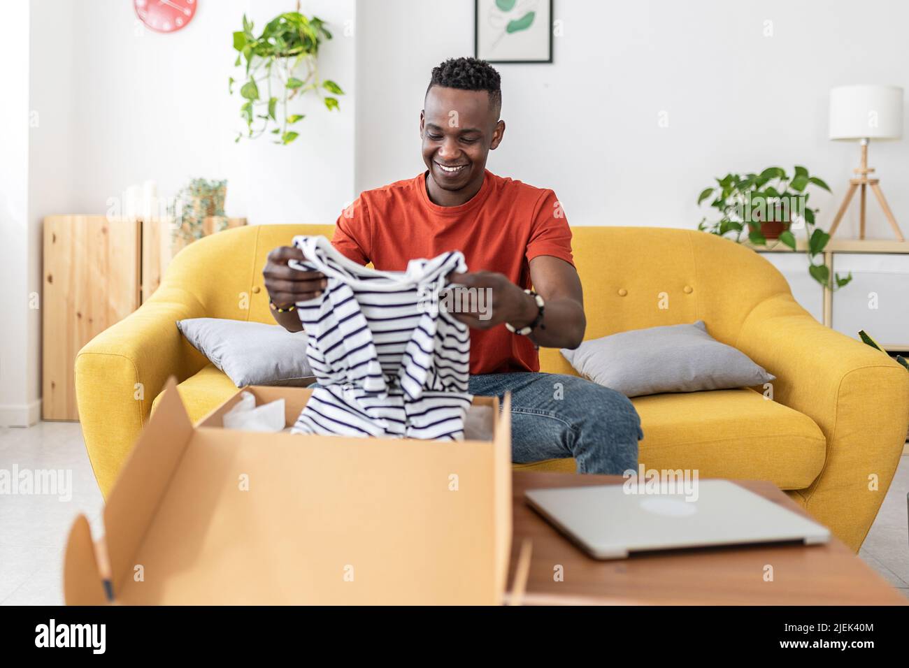 Happy african man opening cardboard box at home Stock Photo