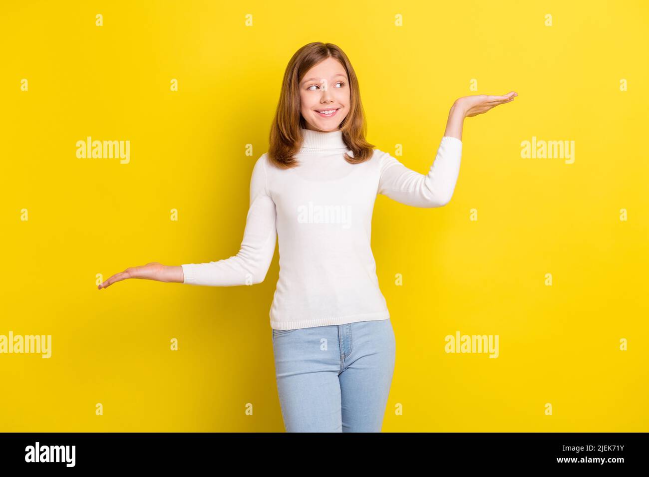 Photo of nice young brown haired little girl look empty space hold hands scales isolated on yellow color background Stock Photo