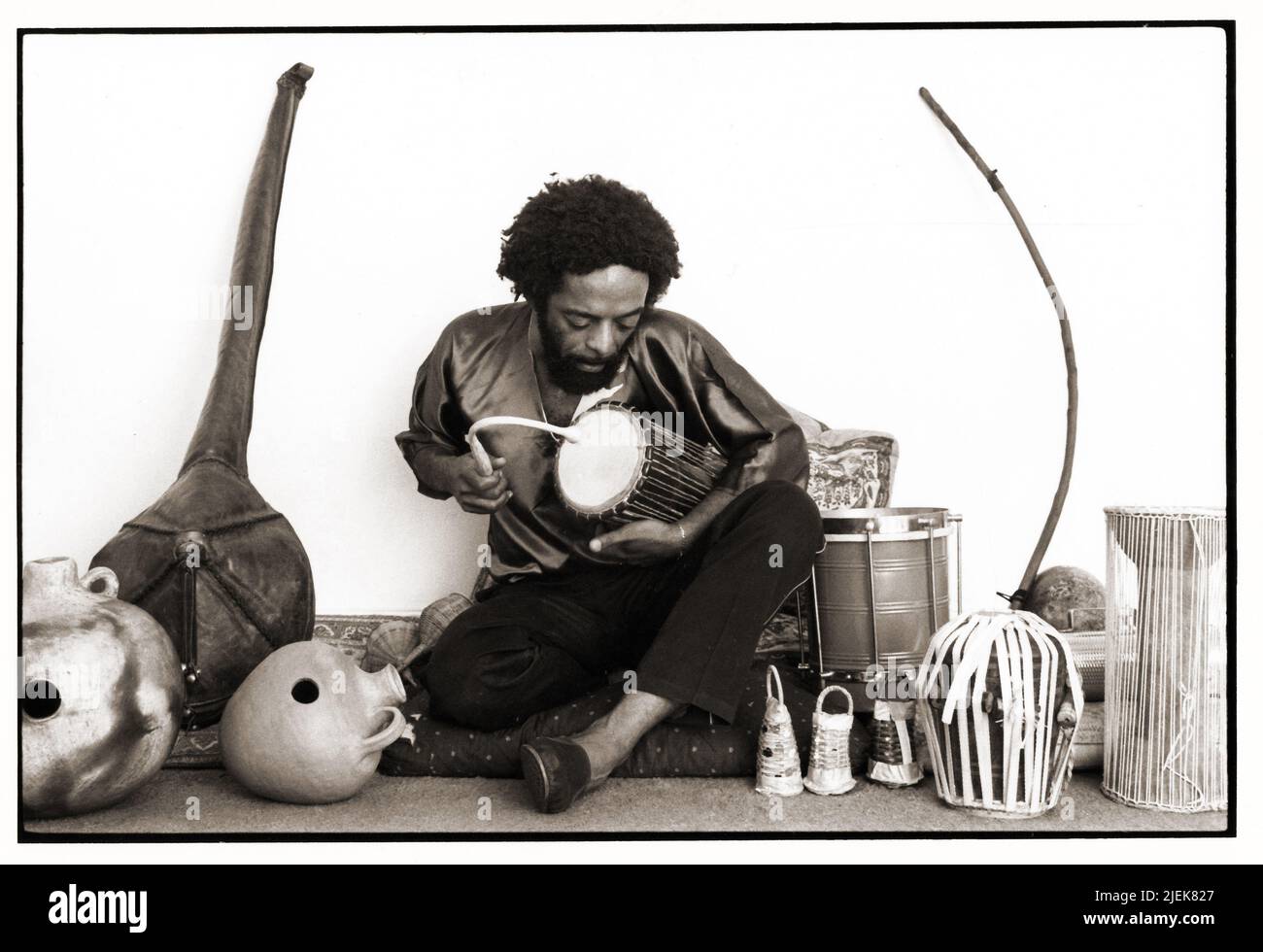 A 1983 posed portrait of Nana Vasconcelos, Brazilian jazz percussionist, playing the dondo talking drum with a curved stick. In New York City. Stock Photo