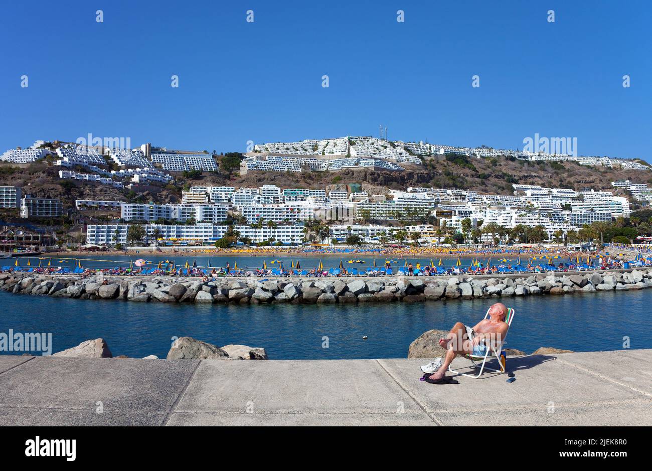 Mann sonnt sich in einer Sonnenliege auf der Mole von Puerto Rico, Gran Canaria, Kanarische Inseln, Spanien, Europa | Elderly man sunbathing on the pi Stock Photo