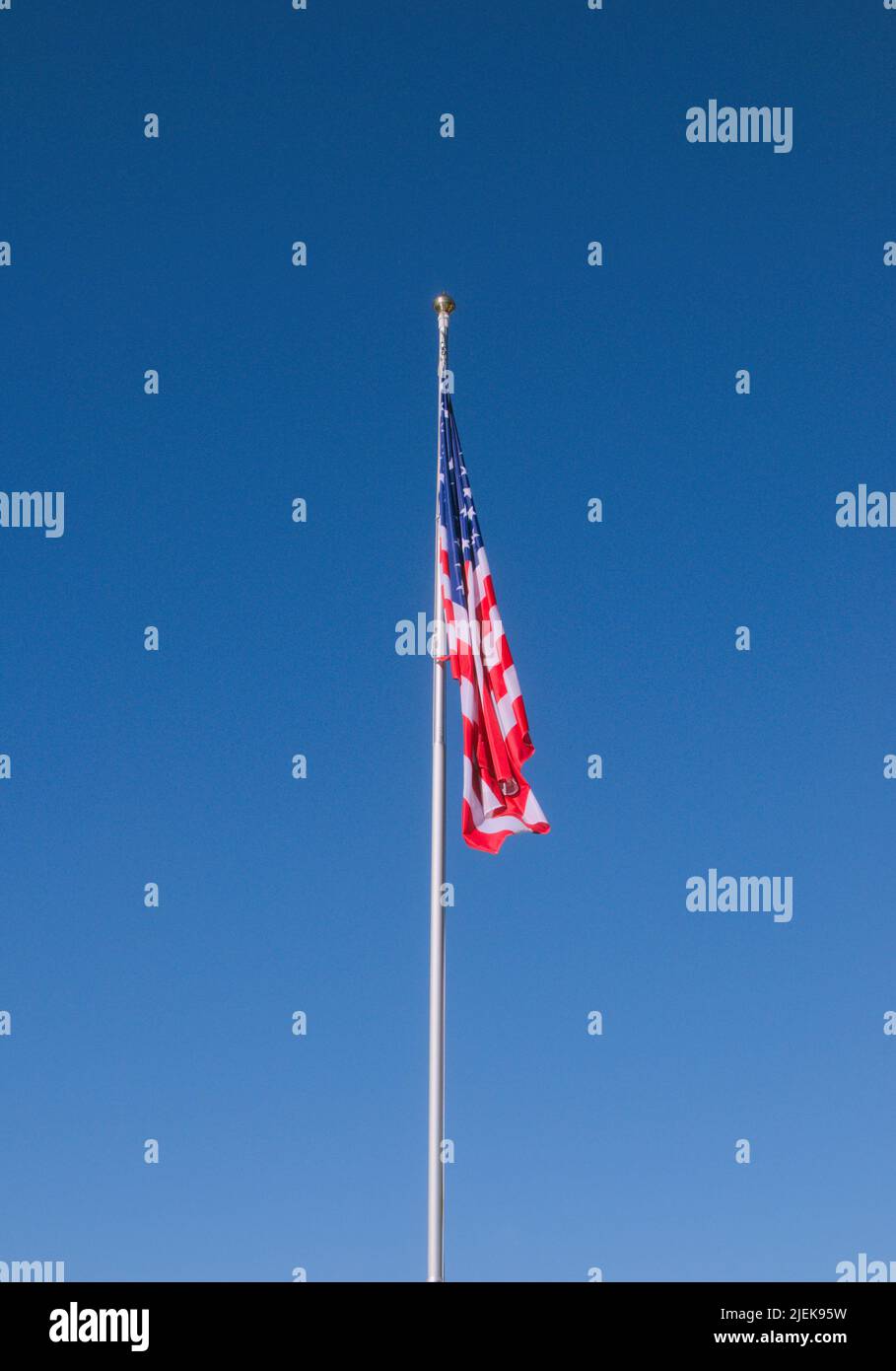 American Flag hanging down against blue sky Stock Photo