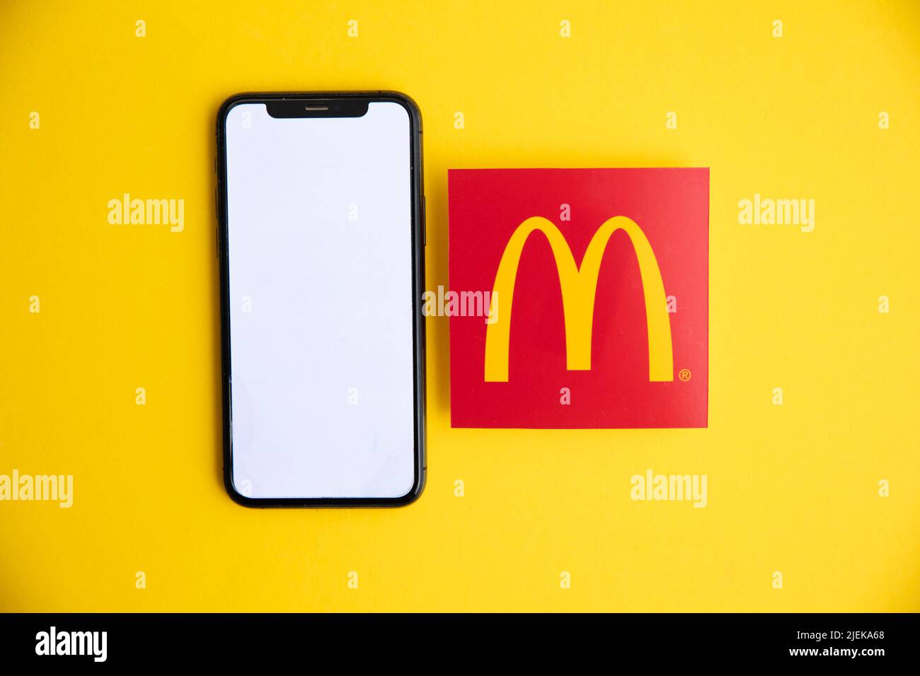 LONDON, UK - June 2022: McDonalds iconic logo with a smartphone. McDonalds is a global fast food business Stock Photo