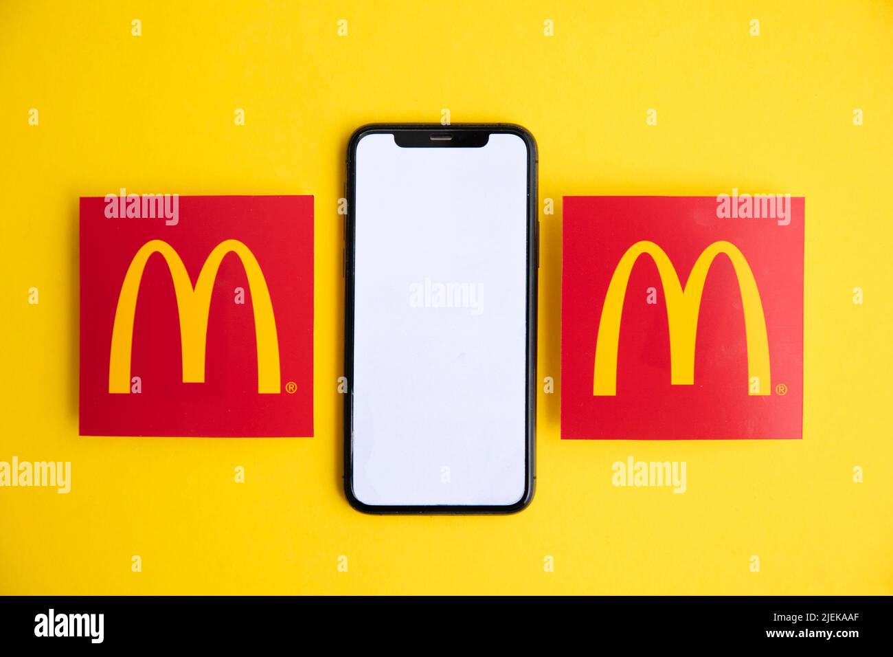 LONDON, UK - June 2022: McDonalds iconic logo with a smartphone. McDonalds is a global fast food business Stock Photo