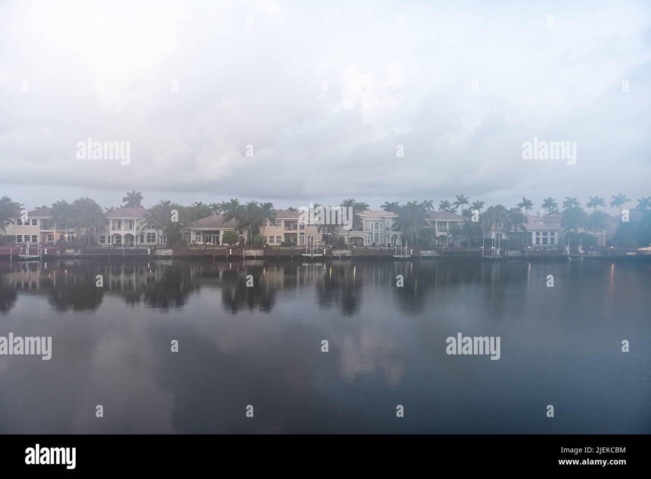 Cloudy foggy mist morning in Hollywood Beach in Miami, Florida Stranahan river and view of waterfront villas houses with palm trees and calm water ref Stock Photo