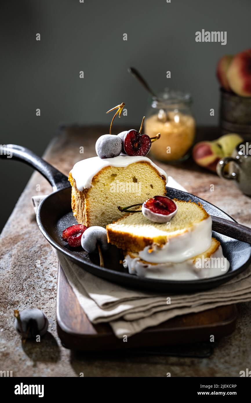 Refreshing lemon cake topped with icing and decorated with iced cherries.Delicious dessert Stock Photo