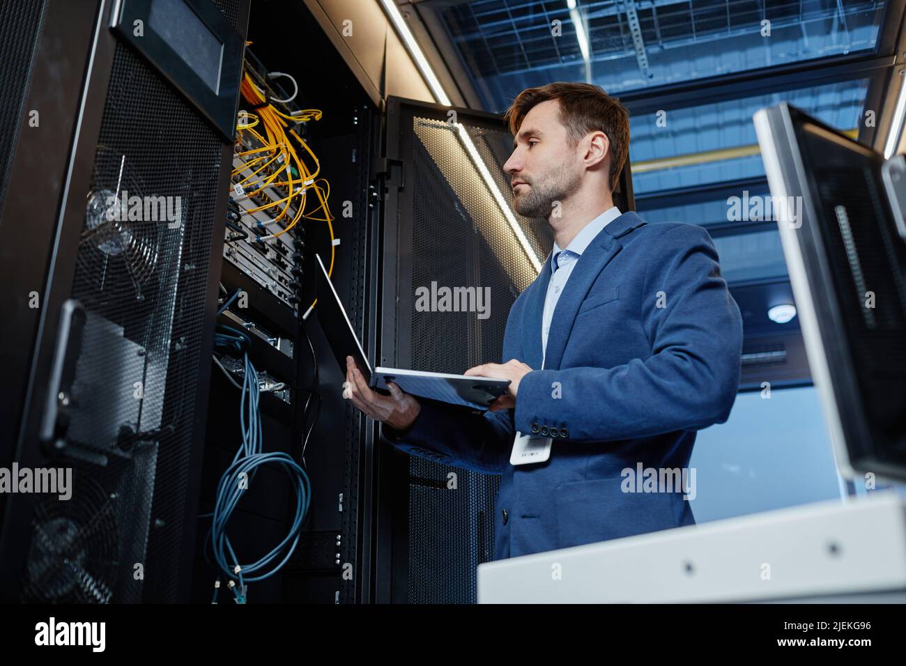 Internet Installation Engineer Low angle portrait of IT engineer holding laptop while setting up ...