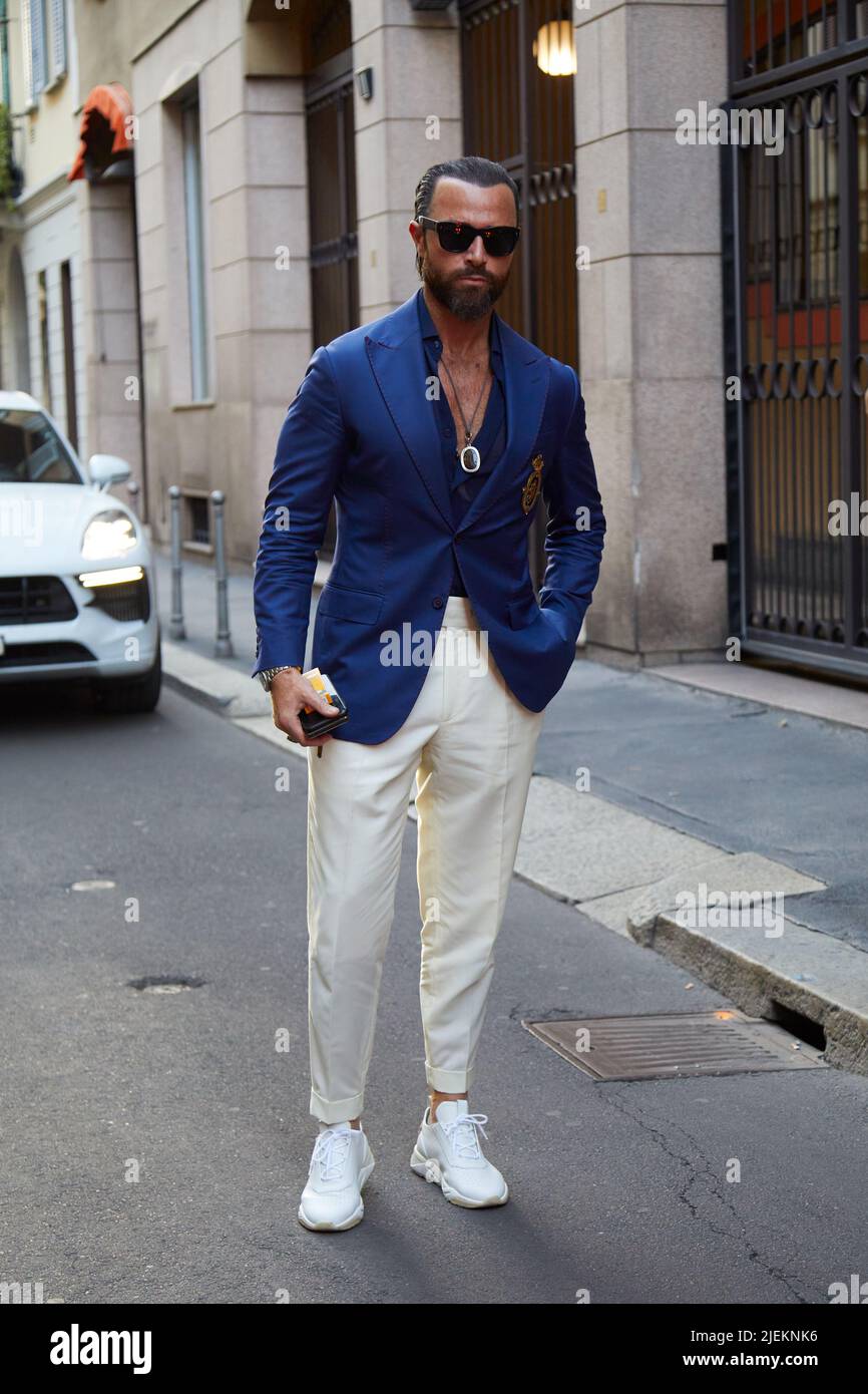 MILAN, ITALY - JUNE 18, 2022: Man with white trousers, sneakers and blue jacket before Versace fashion show, Milan Fashion Week street style Stock Photo