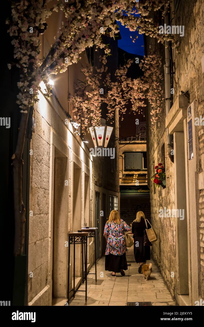 People walking in a narrow alley in the Diocletian's Palace at night, Split, Croatia Stock Photo
