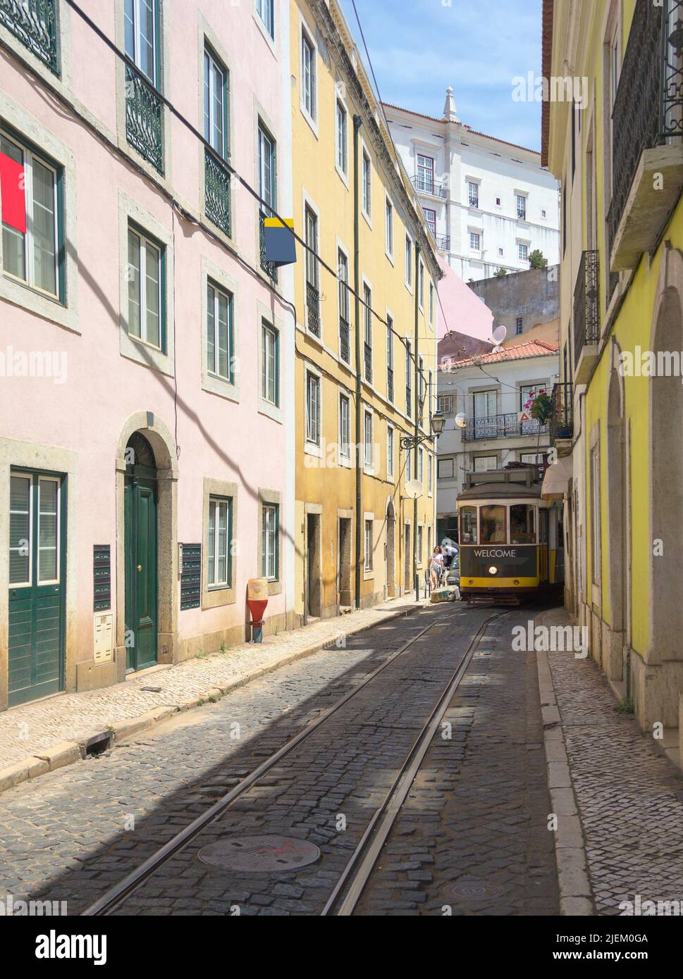 The tram runs along narrow street of Alfama district. Lisbon, Portugal. Stock Photo