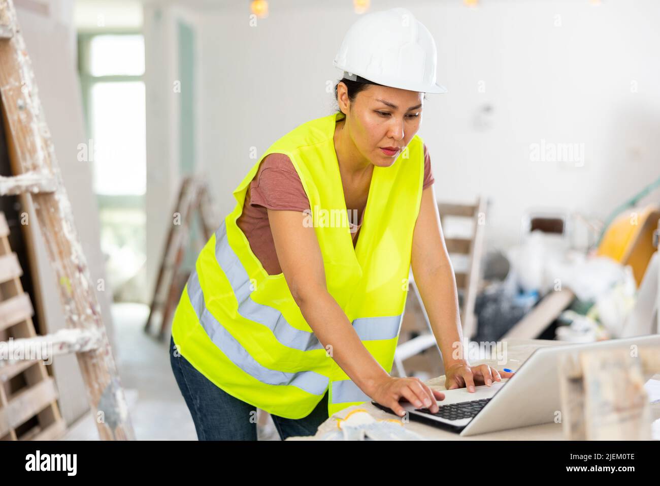 Female architect using laptop during repair works Stock Photo