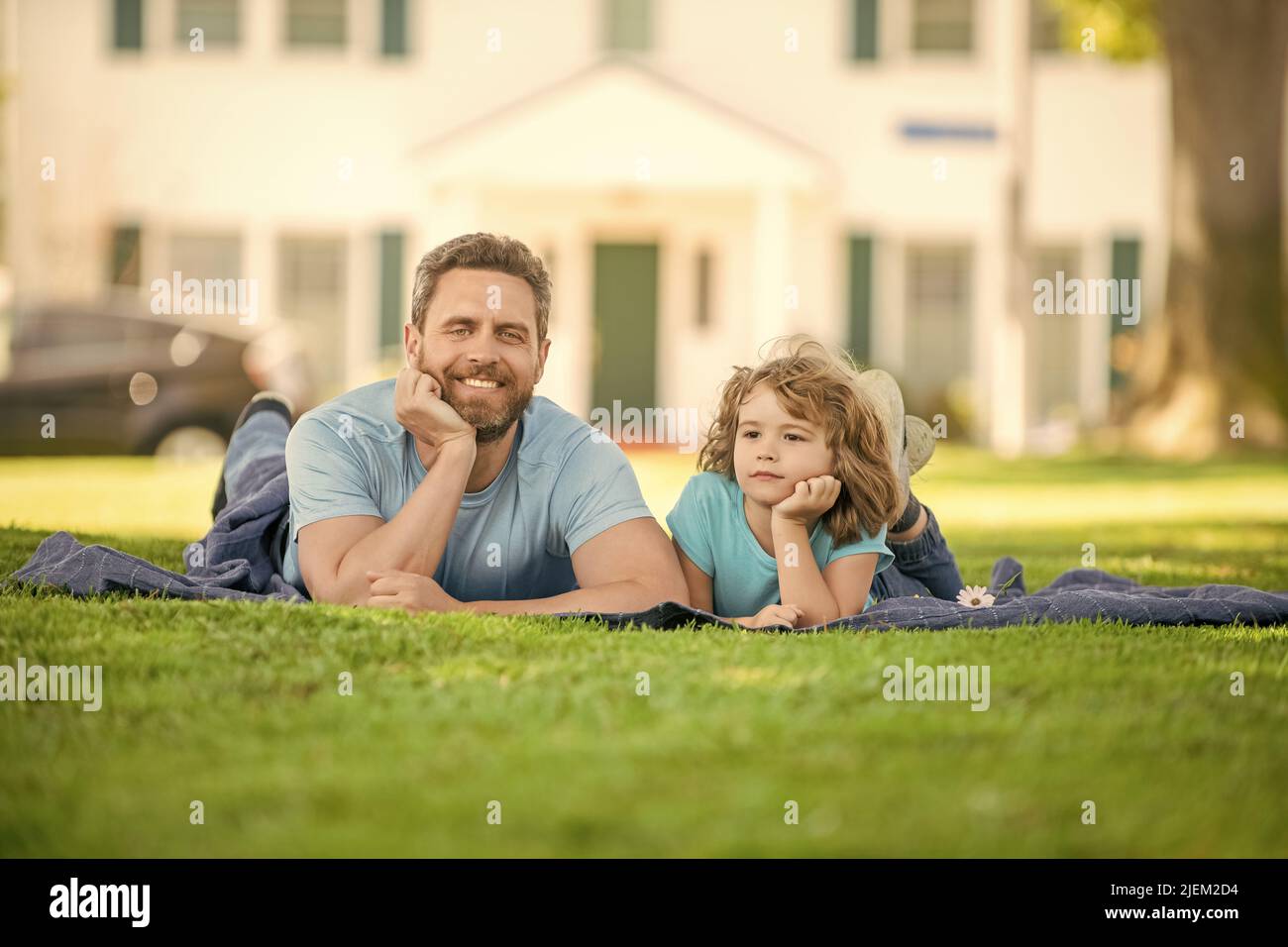 cheerful father with child relax together on green park grass, parenthood Stock Photo