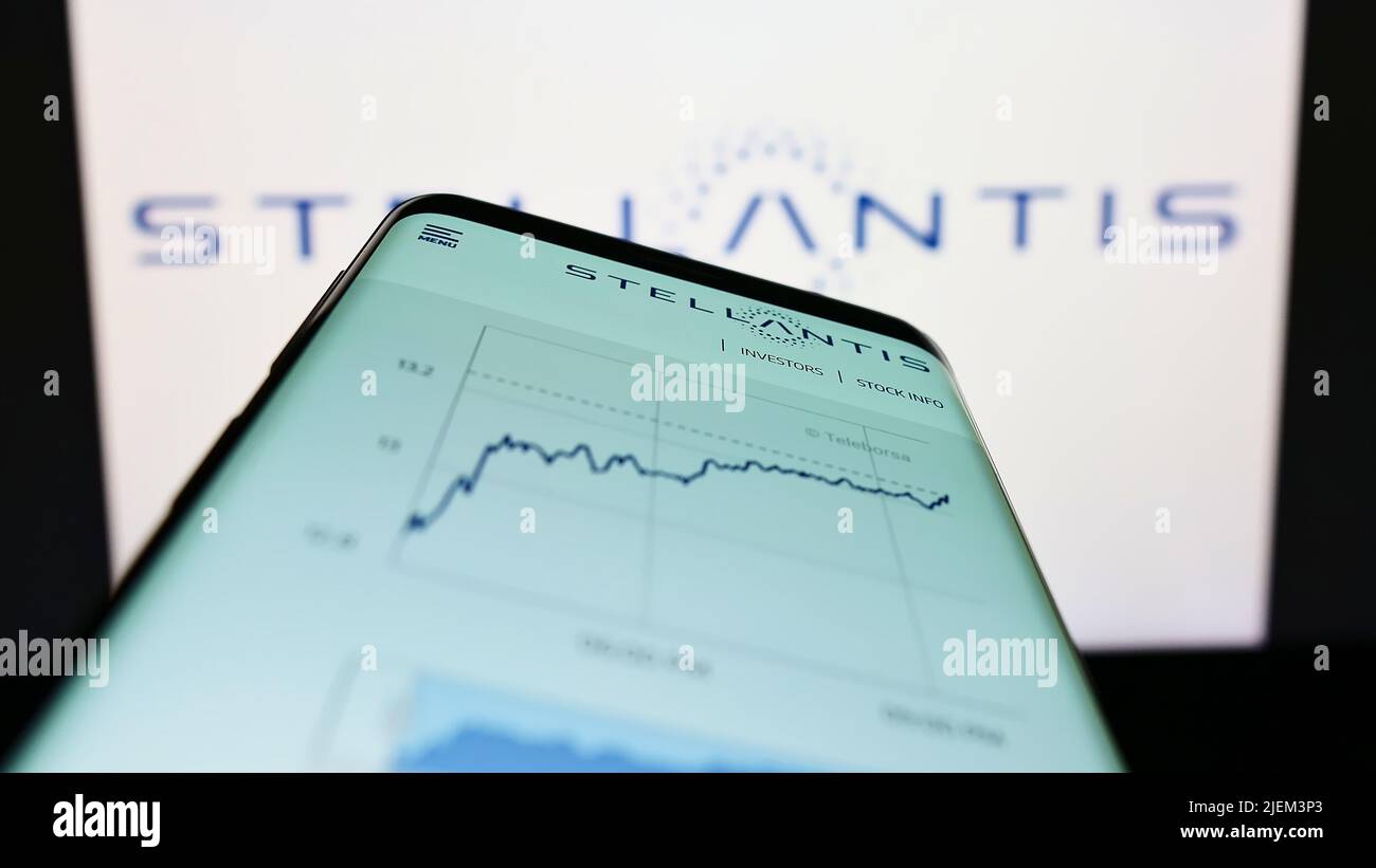 Mobile phone with webpage of car manufacturer Stellantis N.V. on screen in front of business logo. Focus on top-left of phone display. Stock Photo