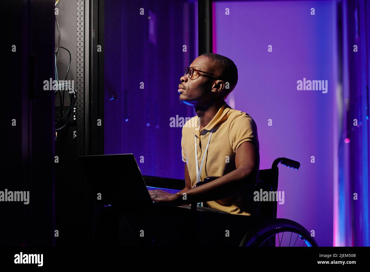 Side view portrait of male system admin with disability using computer while setting up server network Stock Photo