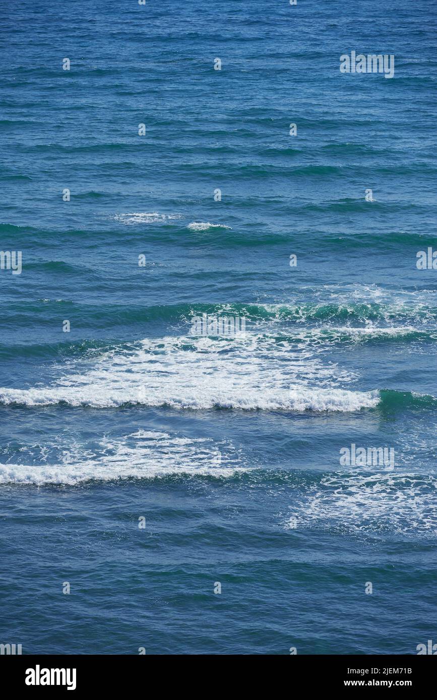 Calm waves in the empty ocean on a sunny day. Beautiful sea water with light ripple effects on the surface. Abstract aqua textures in the deep wide Stock Photo