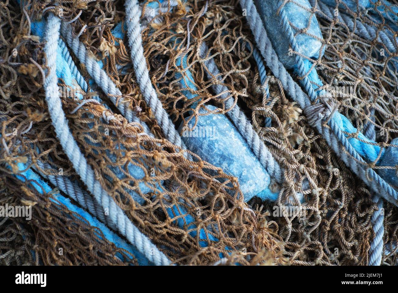 Buoys and a net tangible together as fishing gear or equipment at a harbor. Closeup of blue sea markers and mesh piled, grouped, or gathered together Stock Photo