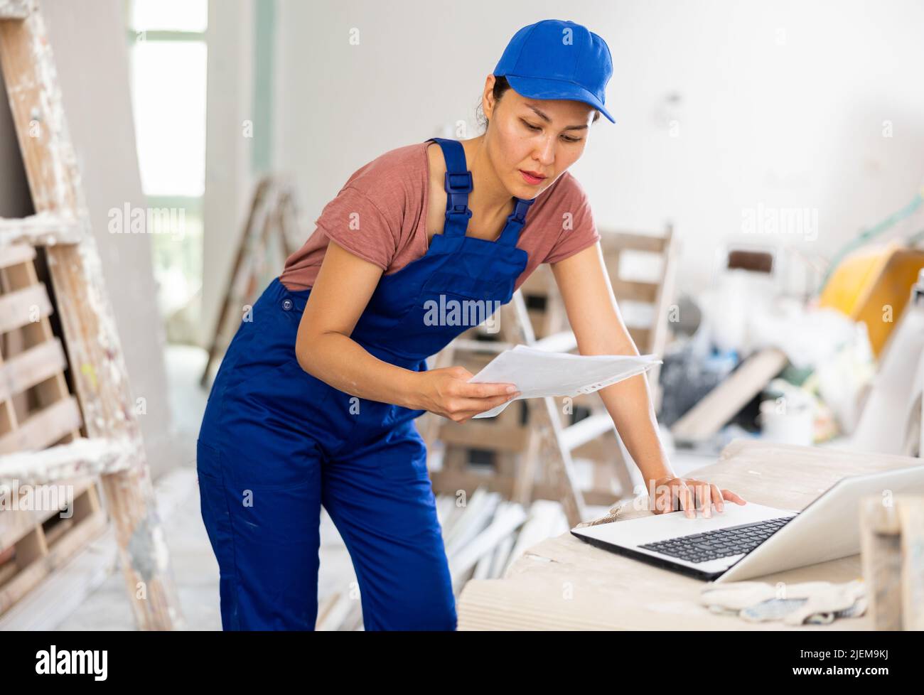 Woman worker checking documents and using laptop in construction site Stock Photo