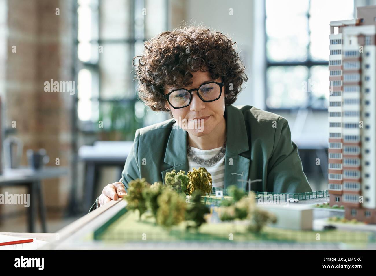 Young female designer in eyeglasses looking at her construction mockup