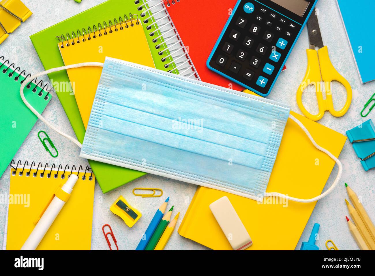 Top view of school supplies and surgical medical mask on blue background. Back to school concept Stock Photo