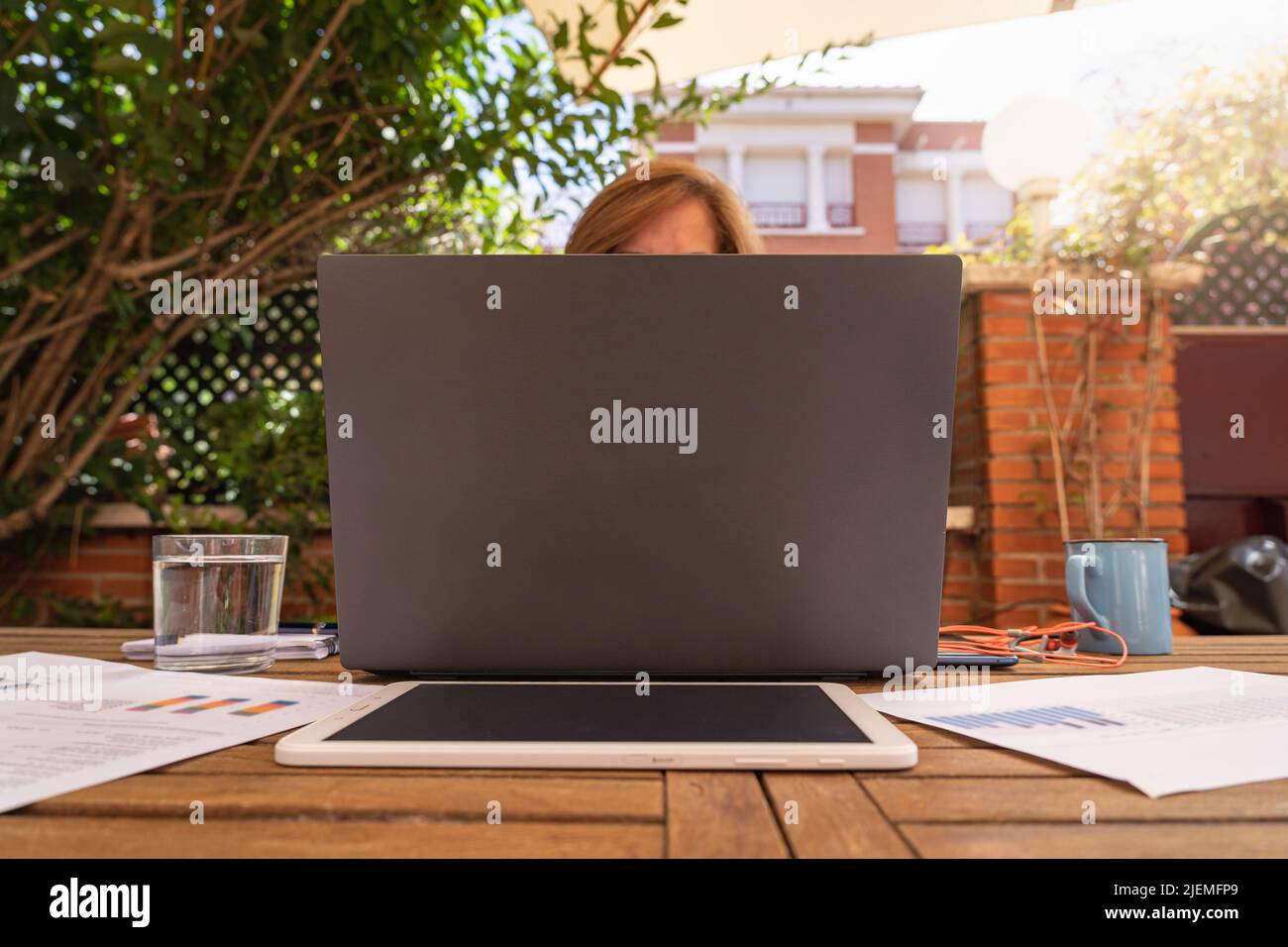Woman teleworking from her home garden with laptop and tablet. Stock Photo
