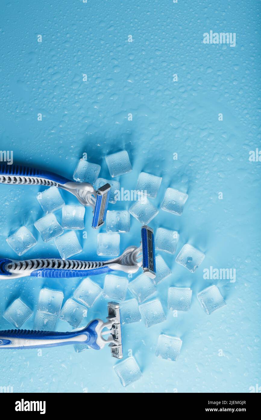 Blue shaving machines in a row on a blue background with ice cubes. The concept of cleanliness and frosty freshness Stock Photo