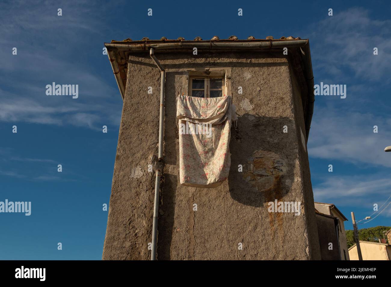 Bed sheet hangs outside the window of an old house in the centro storico of Giuncarico in the Maremma Stock Photo