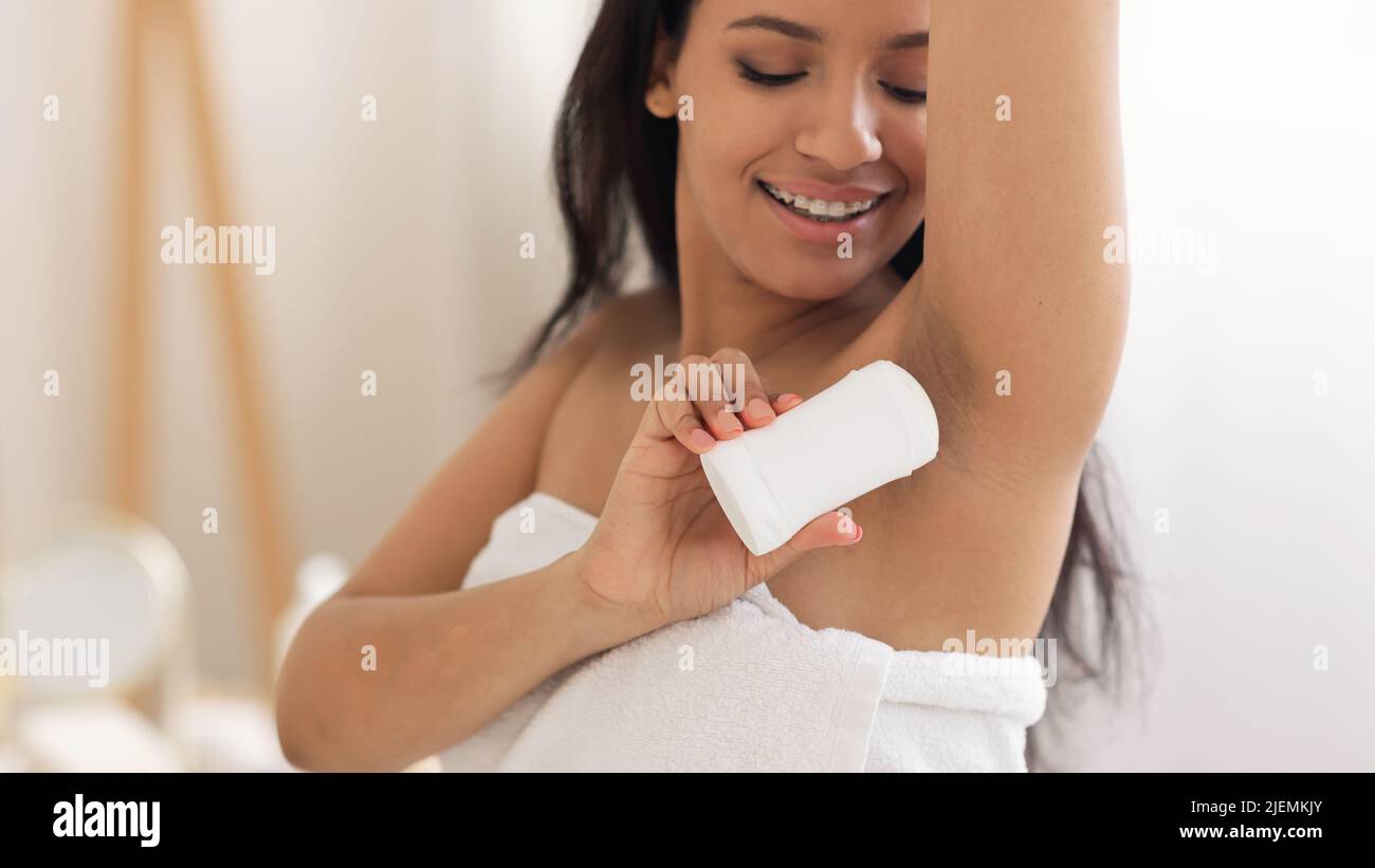Happy Black Lady Applying Antiperspirant On Armpits In Bathroom Stock