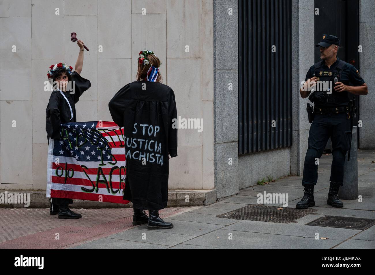 Madrid, Spain. 27th June, 2022. Activists of feminist group FEMEN protesting in front of the US Embassy. Activists are protesting with messages painted on their chests reading 'Roe has fallen but we have not' while they carry an American flag reading 'Abortion is sacred' as they protest against the Supreme Court of the United States decision to overturn abortion rights. Credit: Marcos del Mazo/Alamy Live News Stock Photo