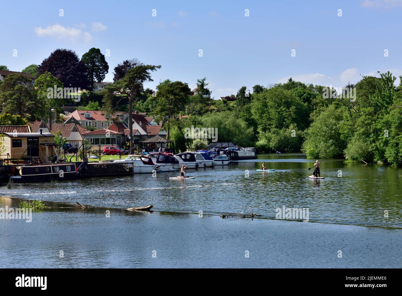 Paddle boarders and boats on the River Avon by weir and Saltford Brass Mill, UK Stock Photo