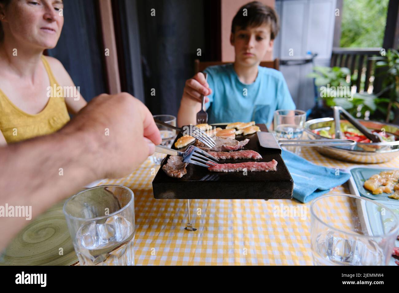 A Family cooking meat on a stone on the terrace of their house. Stock Photo