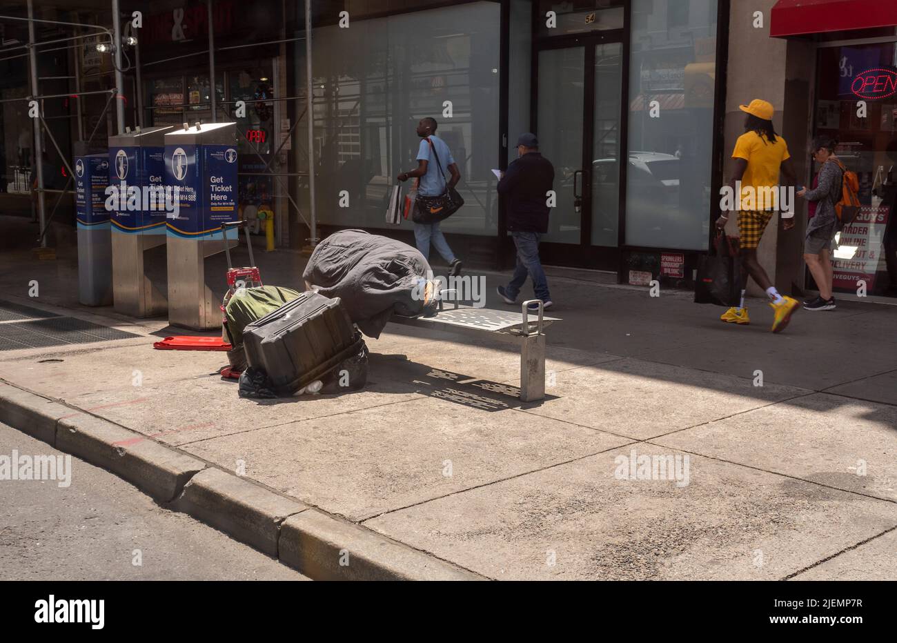 A homeless man sleeps on a bench at a bus stop in New York on Saturday, June 18, 2022. (© Richard B. Levine) Stock Photo