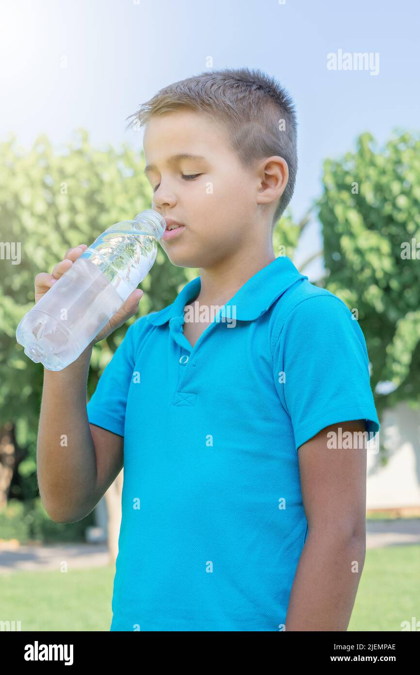 A young boy drinks water from a plastic bottle. Vertical shot Stock