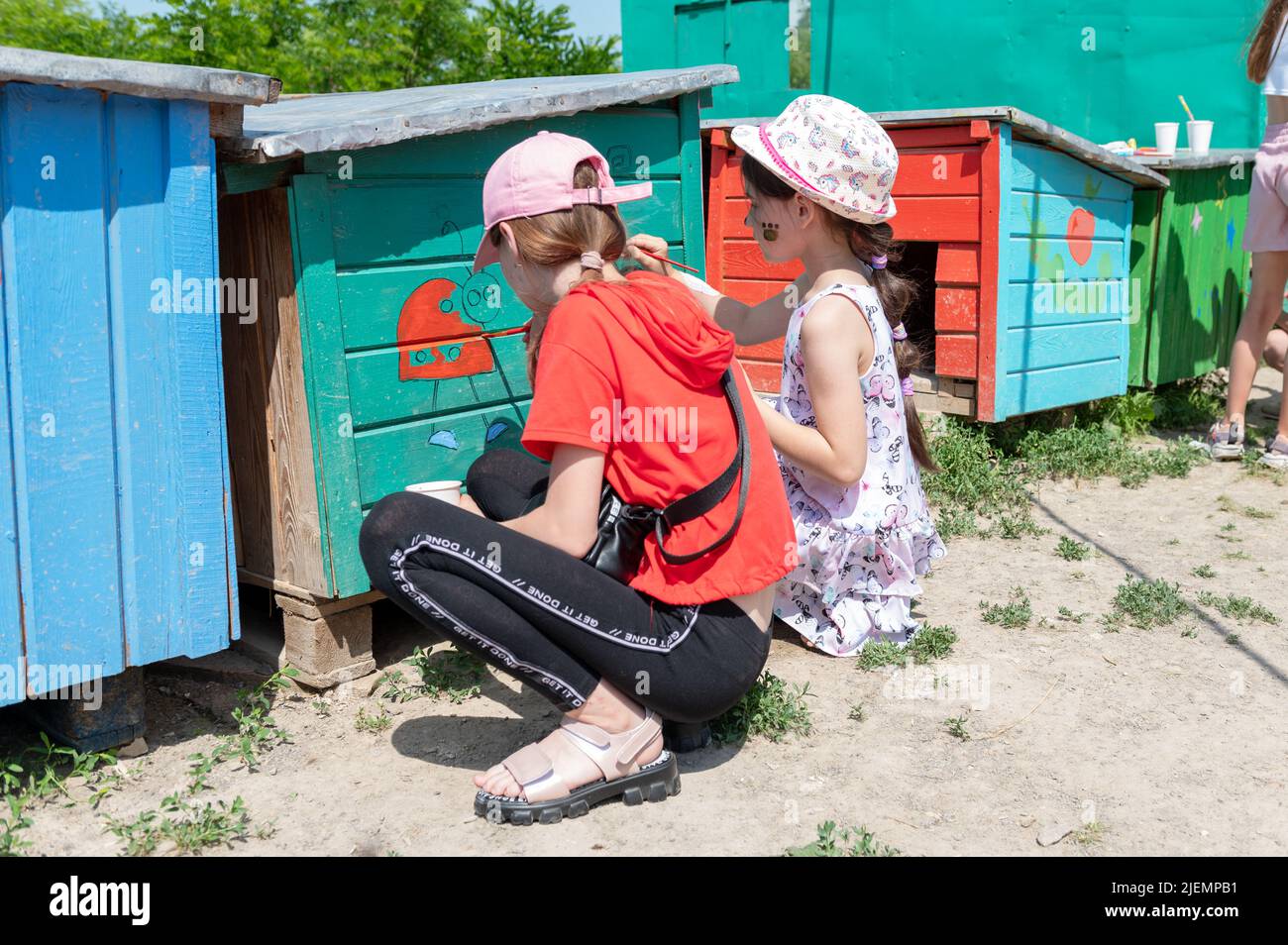 RIVNE, UKRAINE JUNE 19, 2022. Girls painting doghouses. Dog kennels